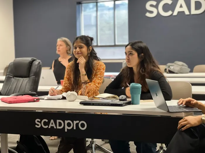 Navyaa in a SCADpro session, listening intently with a classmate.