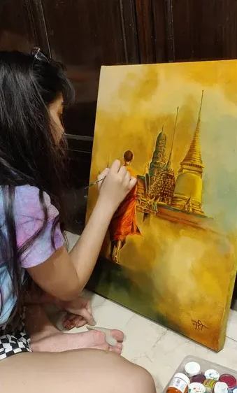 Navyaa painting a golden cityscape on canvas.