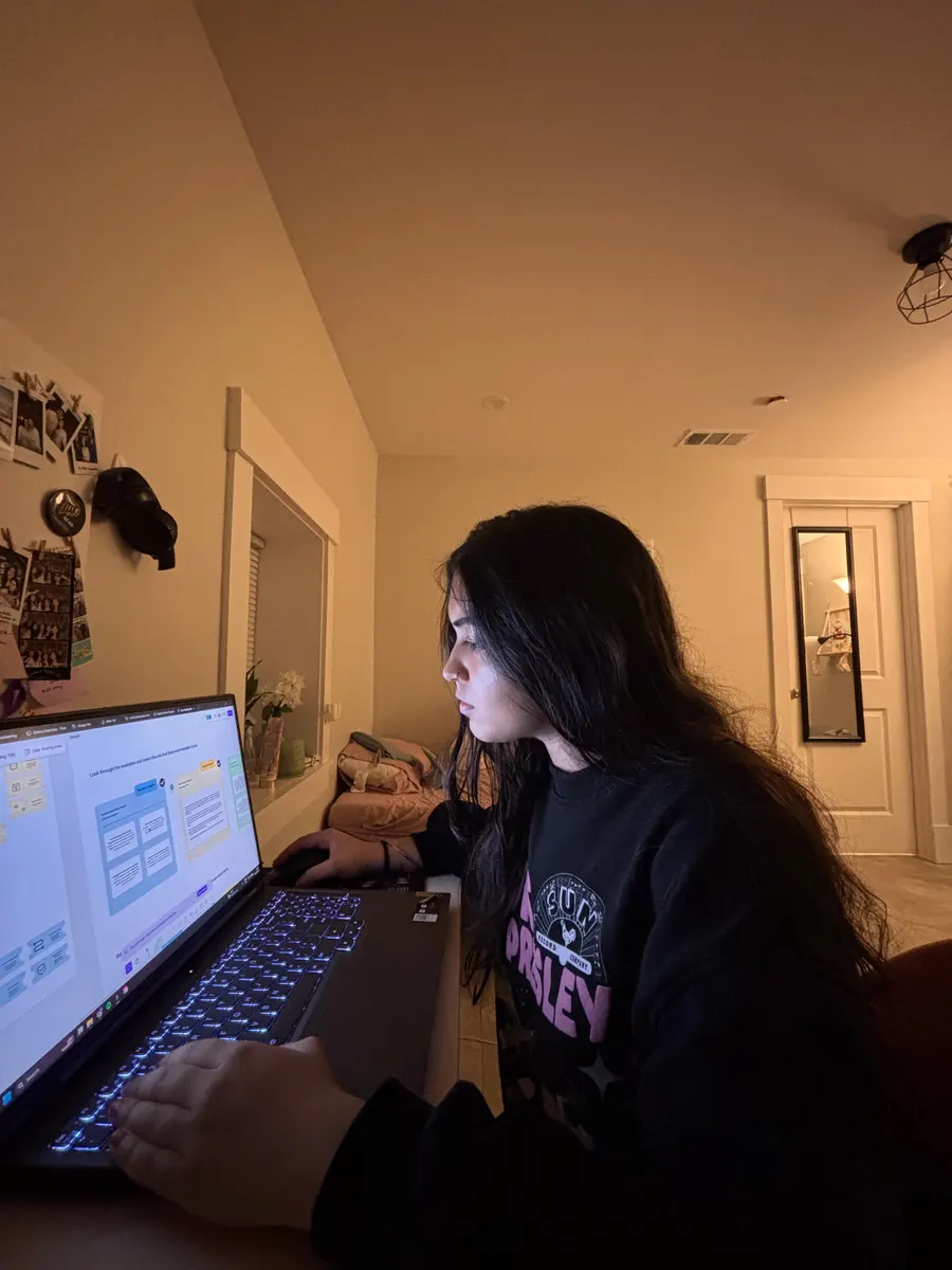 Navyaa working late at her laptop in a lamp-lit room.