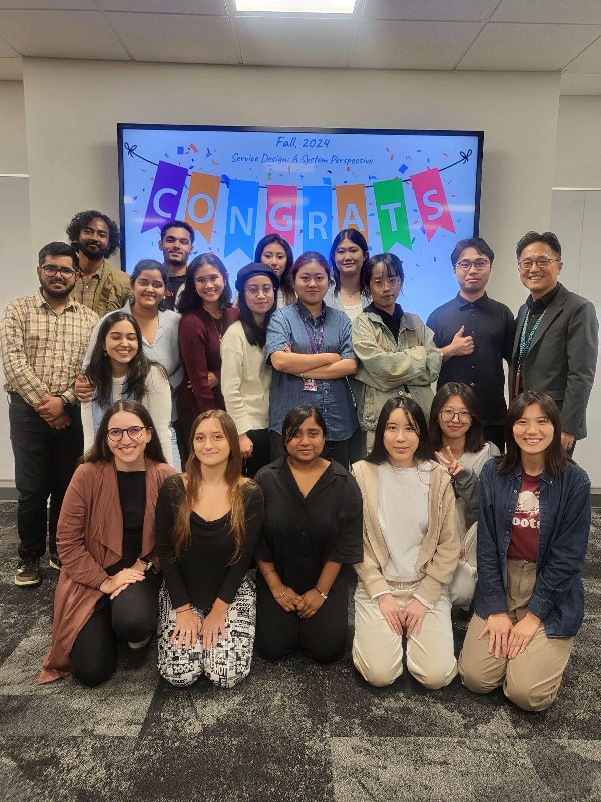 The full class and faculty gathered under a colourful “Congrats” banner after the final presentations.