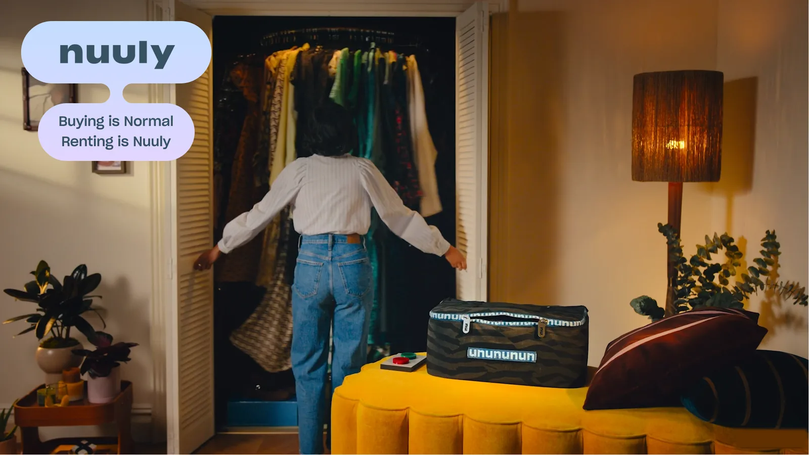 A woman opens her wardrobe beside a Nuuly rental bag, next to the Nuuly logo and the line “Buying is normal, renting is Nuuly.”