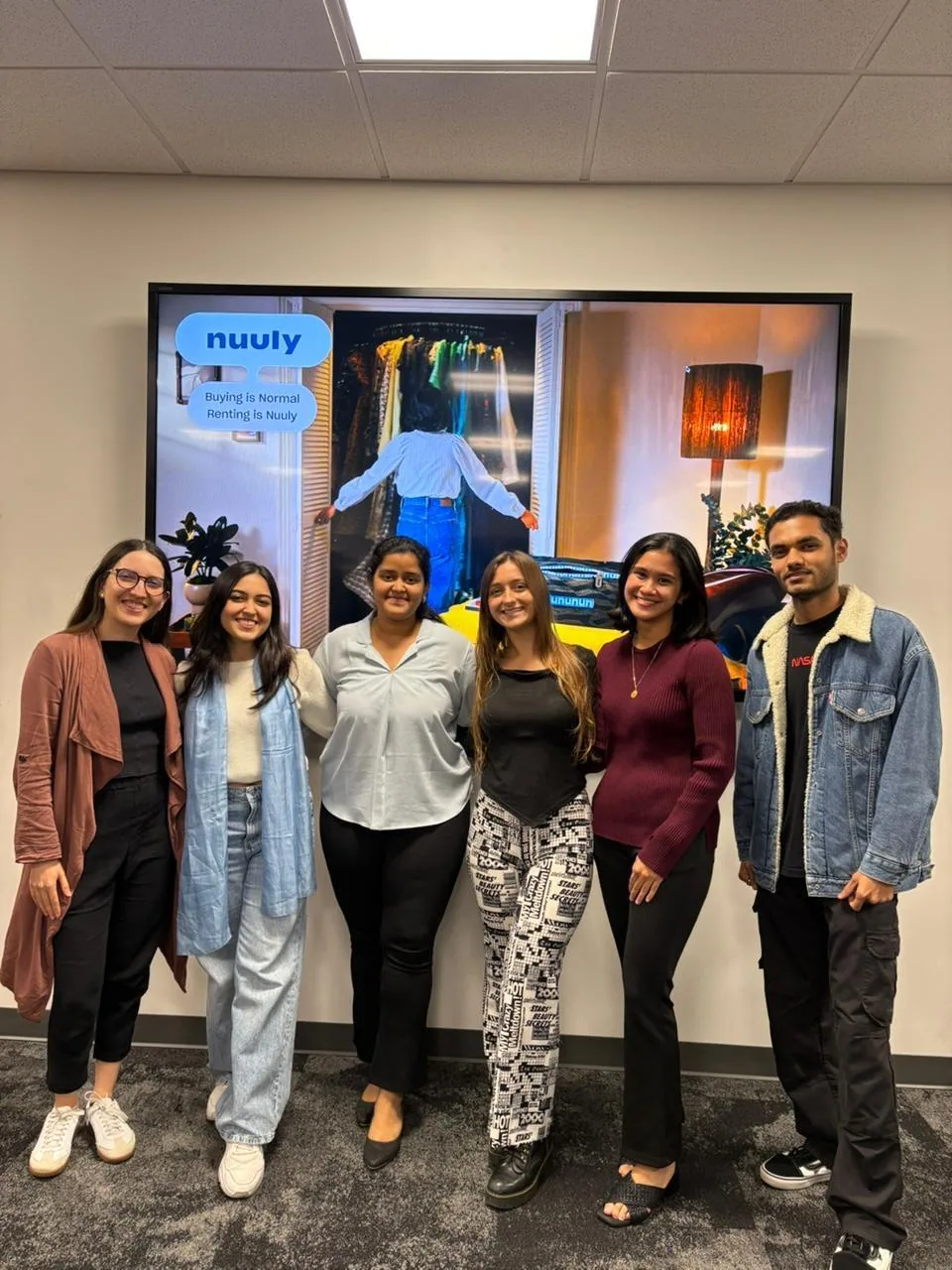 The six-person team smiling in front of the final slide, “Buying is normal, renting is Nuuly.”